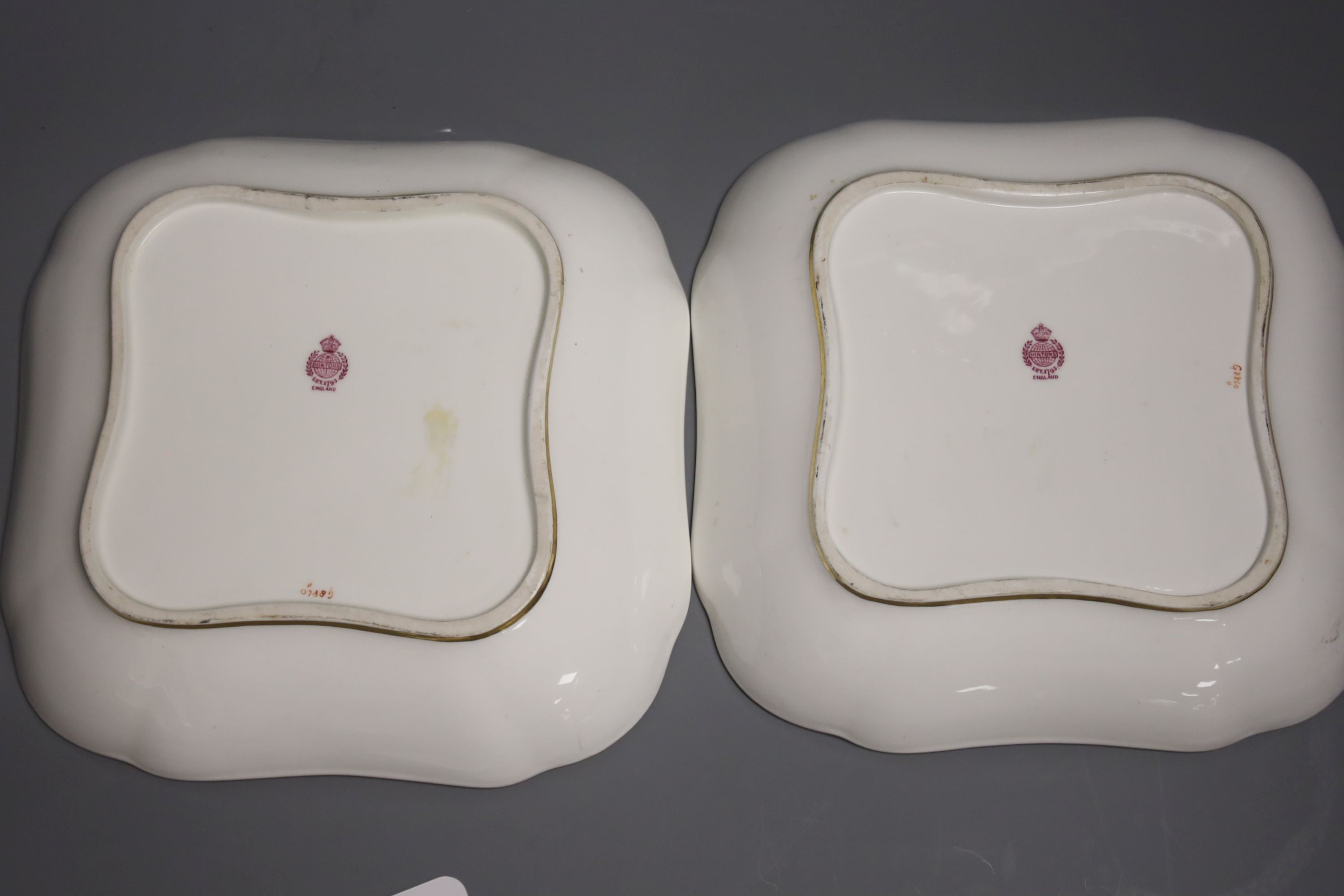 A pair of Minton’s fruit painted dishes of squared form, early 20th century, with tooled gilt borders, signed J C Dean, 21cm diameter.